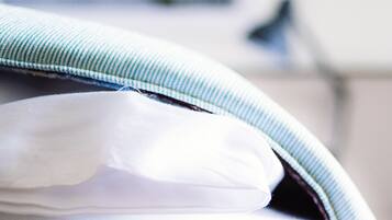 Un gros plan d’un lit avec un drap blanc et un oreiller à rayures bleues.