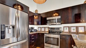 Una cocina moderna con electrodomésticos de acero inoxidable, gabinetes de madera oscura y encimera de granito.