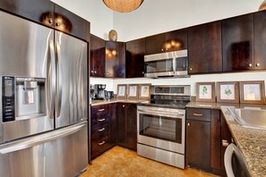Una cocina moderna con electrodomésticos de acero inoxidable, gabinetes de madera oscura y encimera de granito.