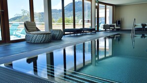 An indoor swimming pool with clear views of a mountainous landscape through large windows. - VIU Hotel Villars (Ollon)