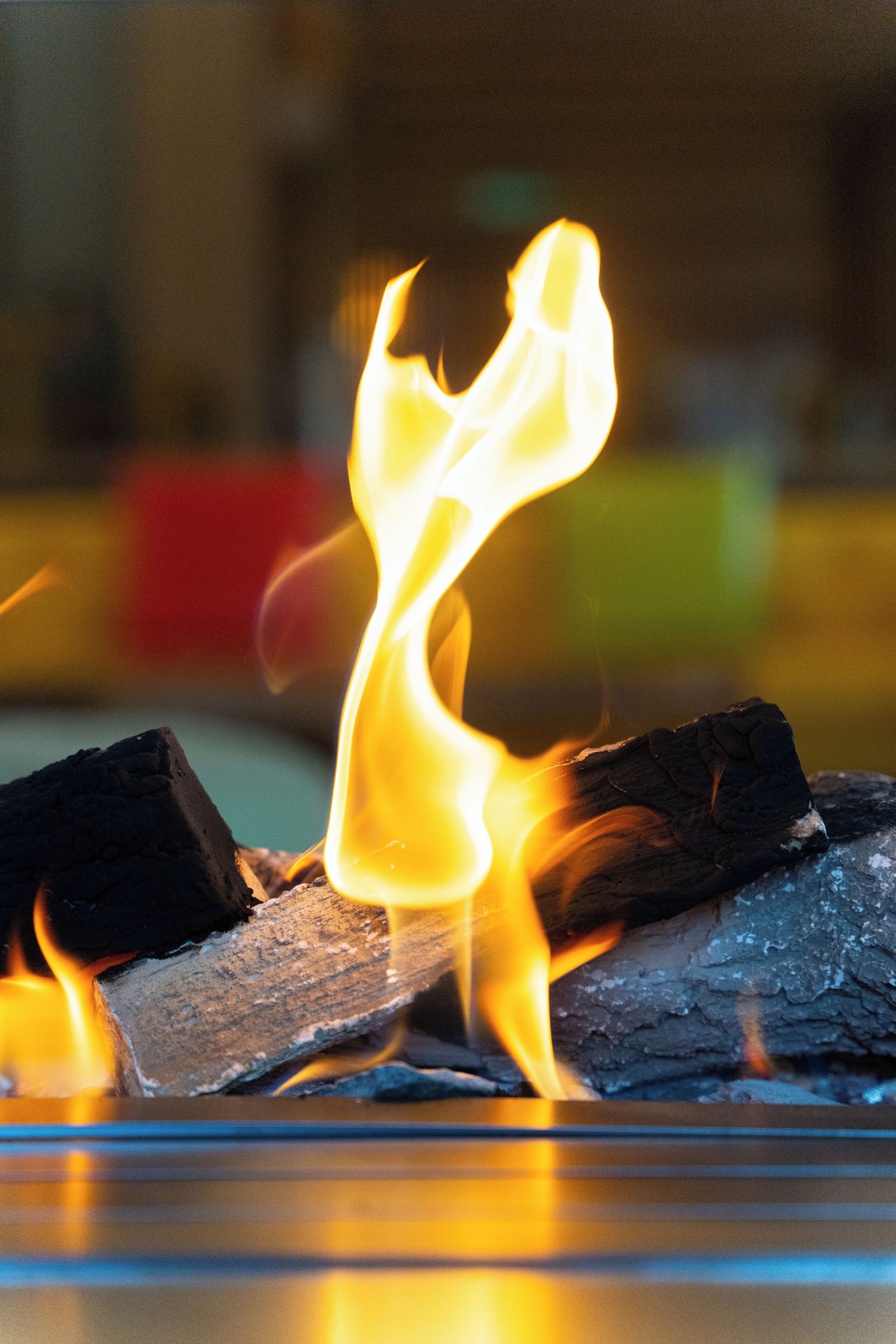 A close-up of a fire with flames licking a charcoal piece.