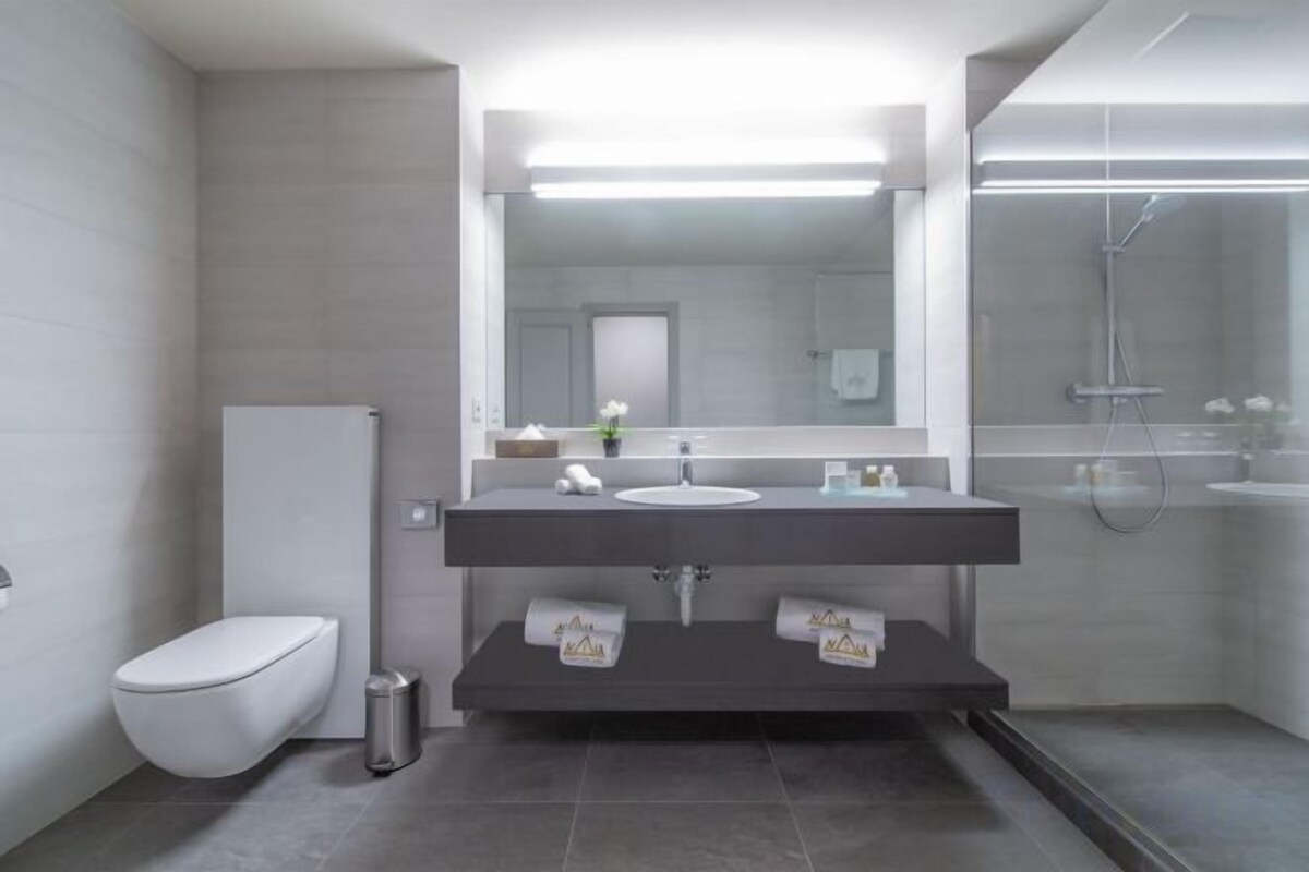 A modern bathroom with a toilet, sink, and shower.