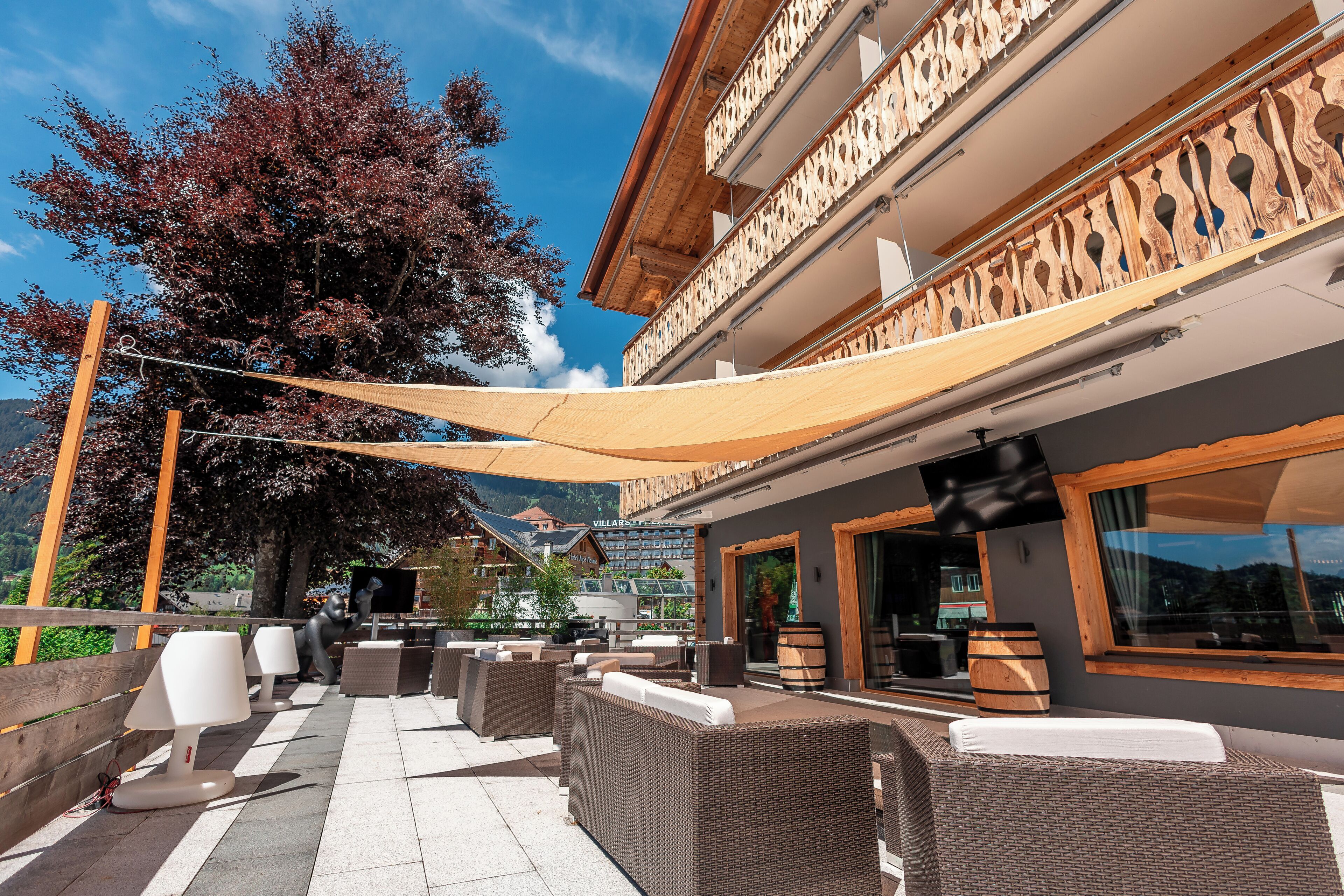 Ein Außenbereich mit Korbmöbeln, einer Holzpergola und Blick auf einen Berg.