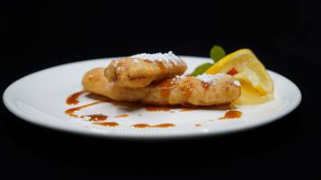 A plate with two fried pastries, a lemon slice, and a mint leaf.