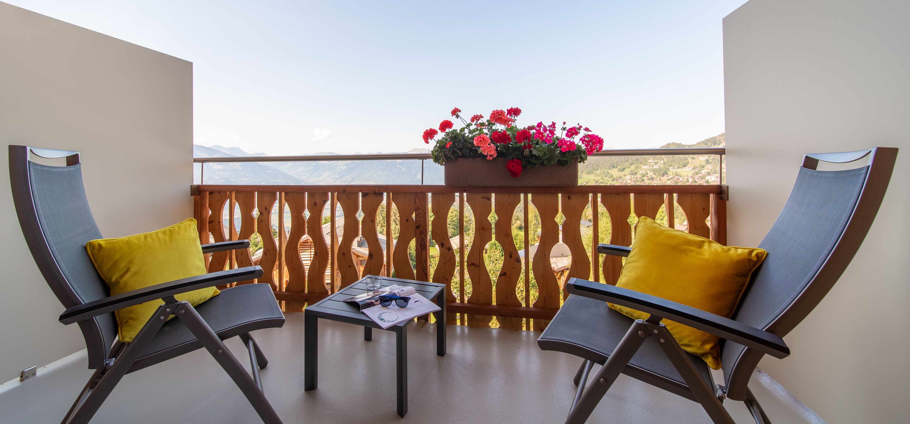 A balcony with two chairs, a table, and a flower box.
