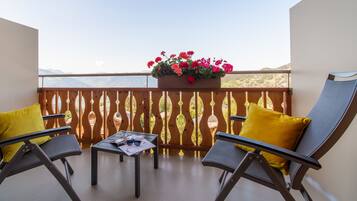A balcony with two chairs, a table, and a flower box.