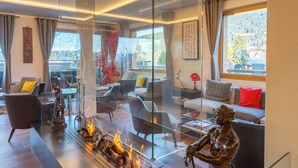 A modern living room with a glass partition, a fireplace, and a statue. - VIU Hotel Villars (Ollon)
