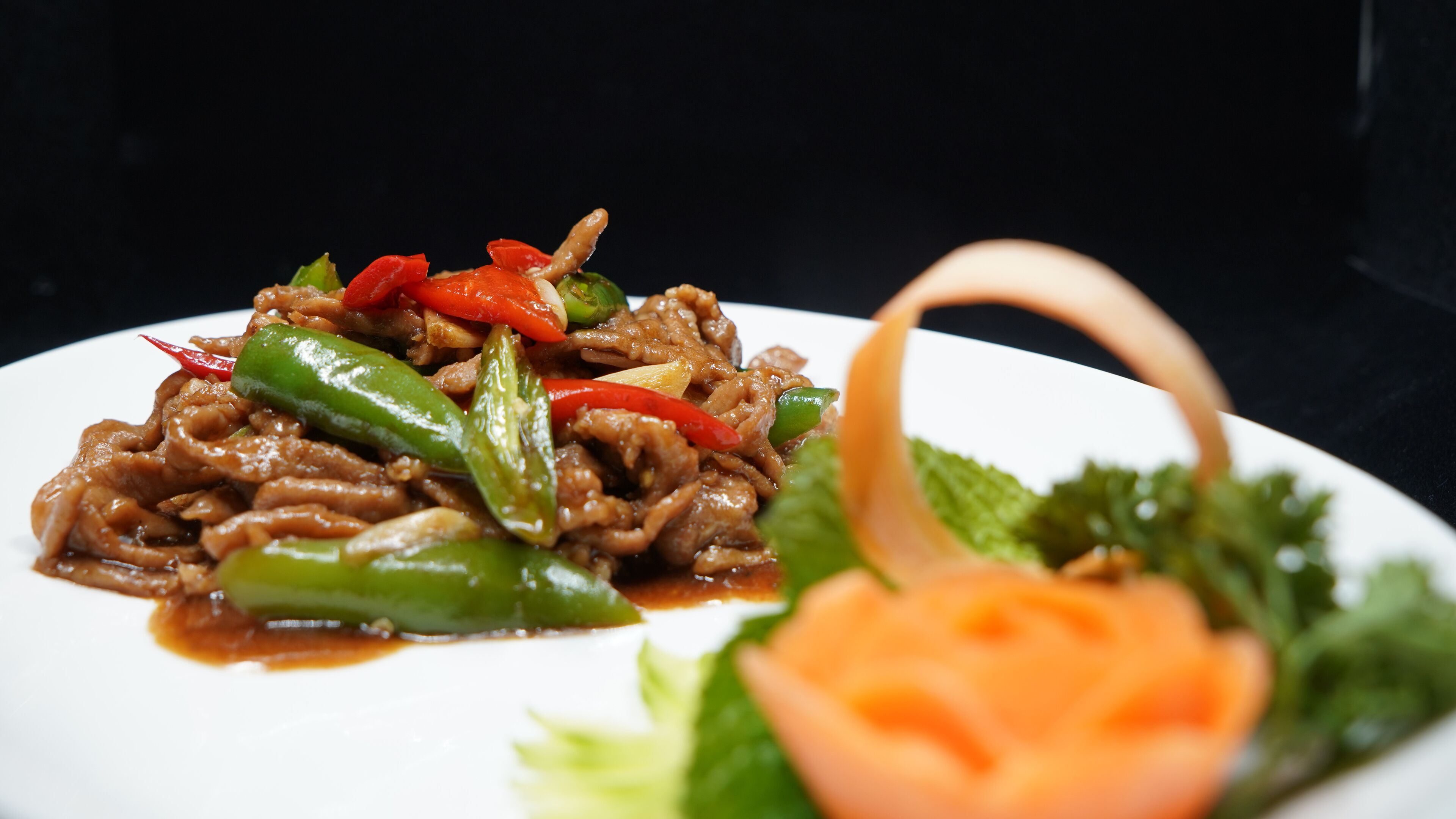 A plate of stir-fried beef with vegetables and a side of fresh salad.