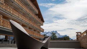 A modern building with multiple balconies and a view of snow-capped mountains. - VIU Hotel Villars (Ollon)
