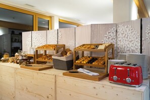 A breakfast buffet with various baked goods and a red toaster. - VIU Hotel Villars (Ollon)