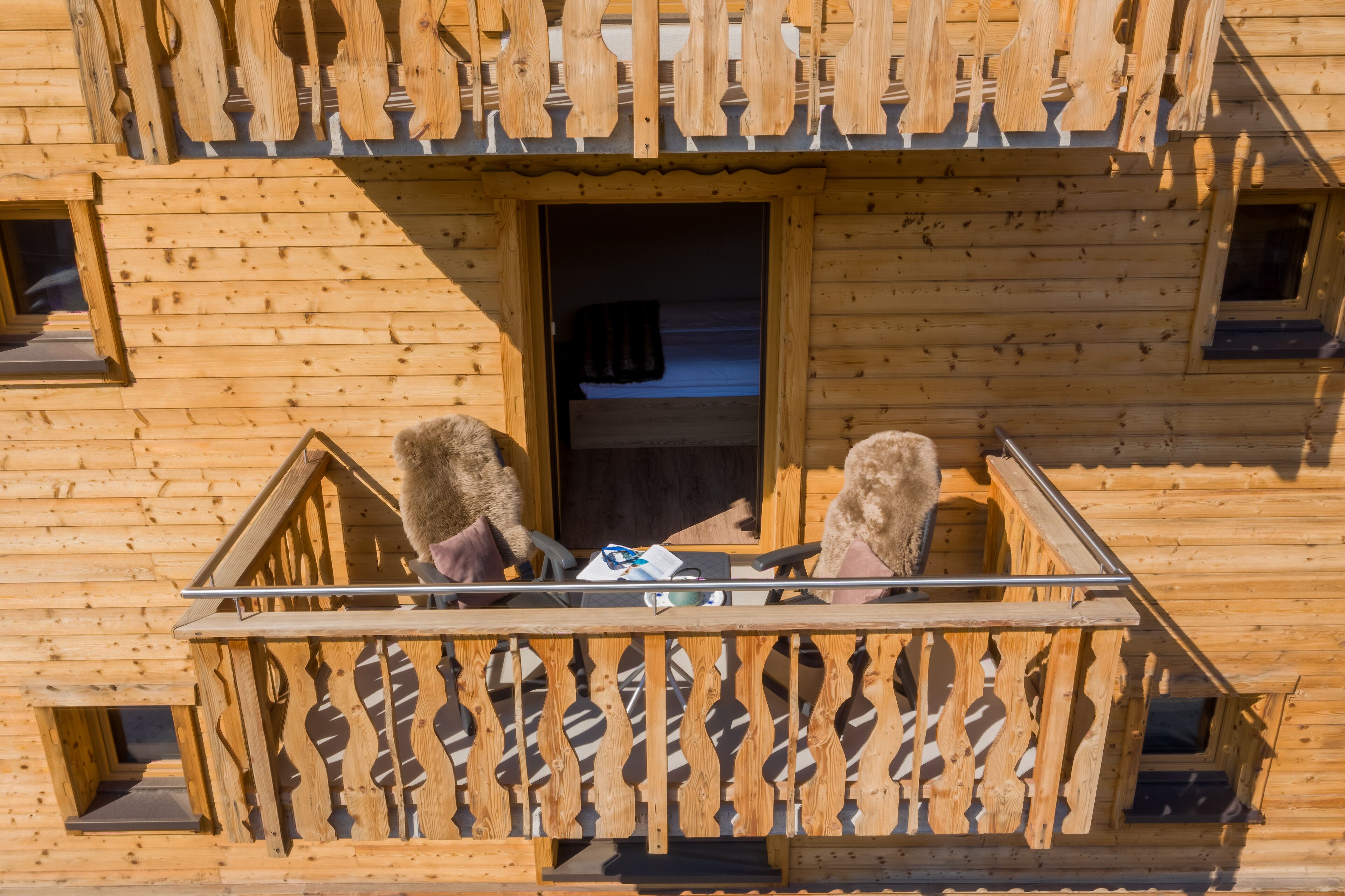 A wooden cabin with a balcony featuring a wooden railing and a small window.