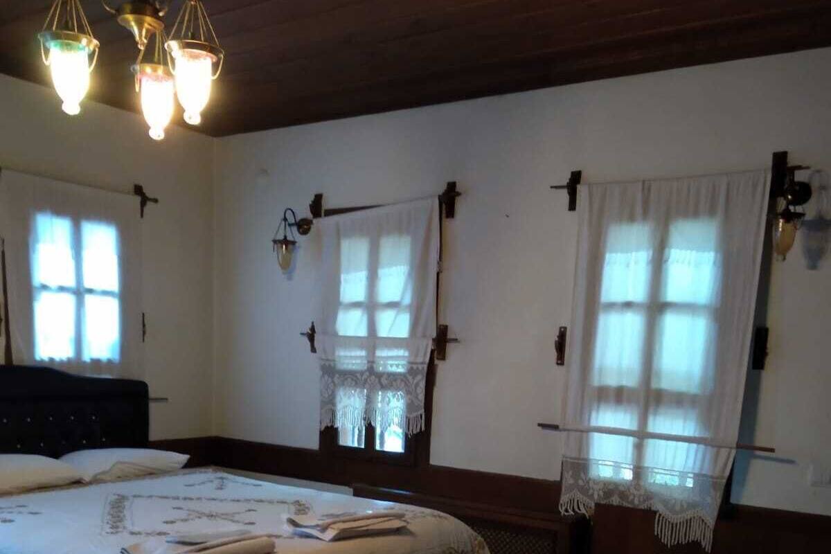 A room with two beds, wooden ceiling beams, and a chandelier.