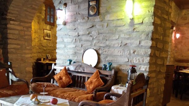 A rustic interior with stone walls, wooden furniture, and a patterned rug. - Safranbolu Konagi (Safranbolu)