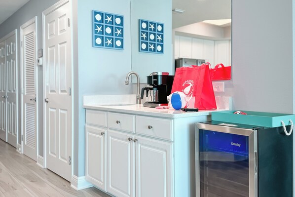 A modern kitchen with a built-in coffee maker, a mini fridge, and a red shopping bag on the counter.