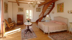 Une chambre avec un escalier en bois, un lit, une chaise, une table et un lustre.