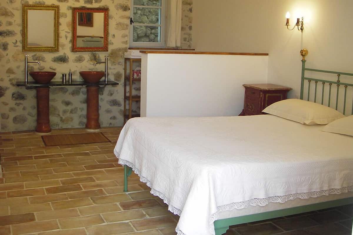 Une chambre à coucher avec un lit, deux lavabos, un miroir et une fenêtre.