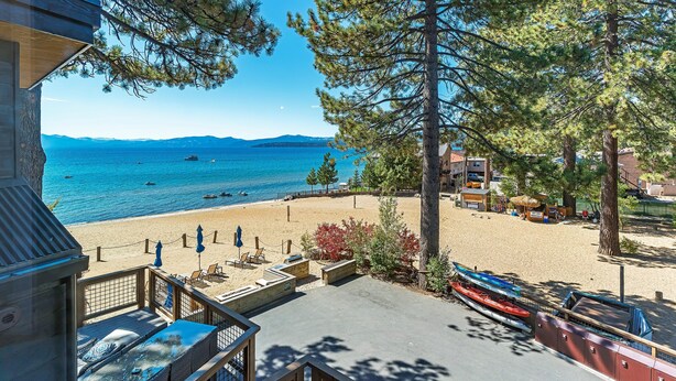 A beach view with boats, a wooden deck, and a building with a balcony.