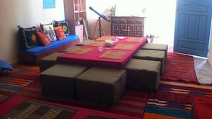 Una habitación con un sofá, otomanas, una mesa con papeles, un telescopio y una estantería.