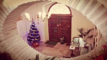 A room with a Christmas tree, a chandelier, and a door with a decorative arch.