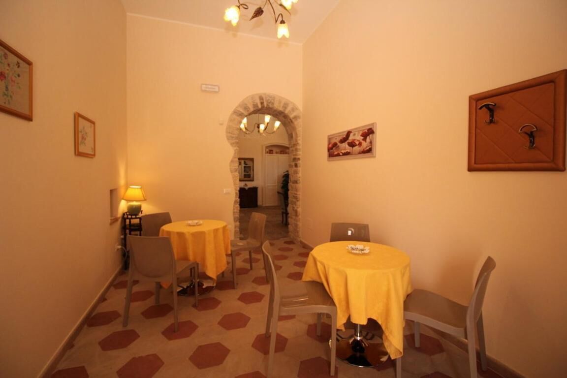 A dining area with hexagonal patterned carpet, round tables with yellow tablecloths, and chairs.