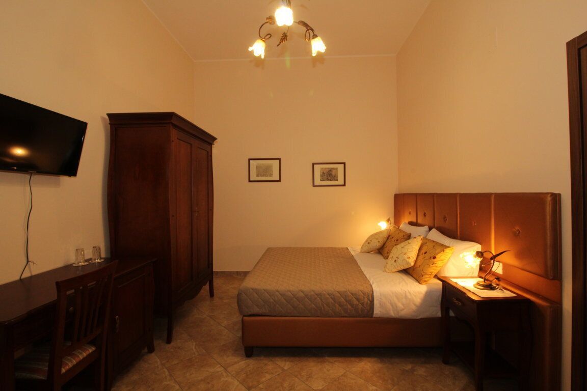 Une chambre à coucher avec un lit, un bureau, une télévision et un lustre.
