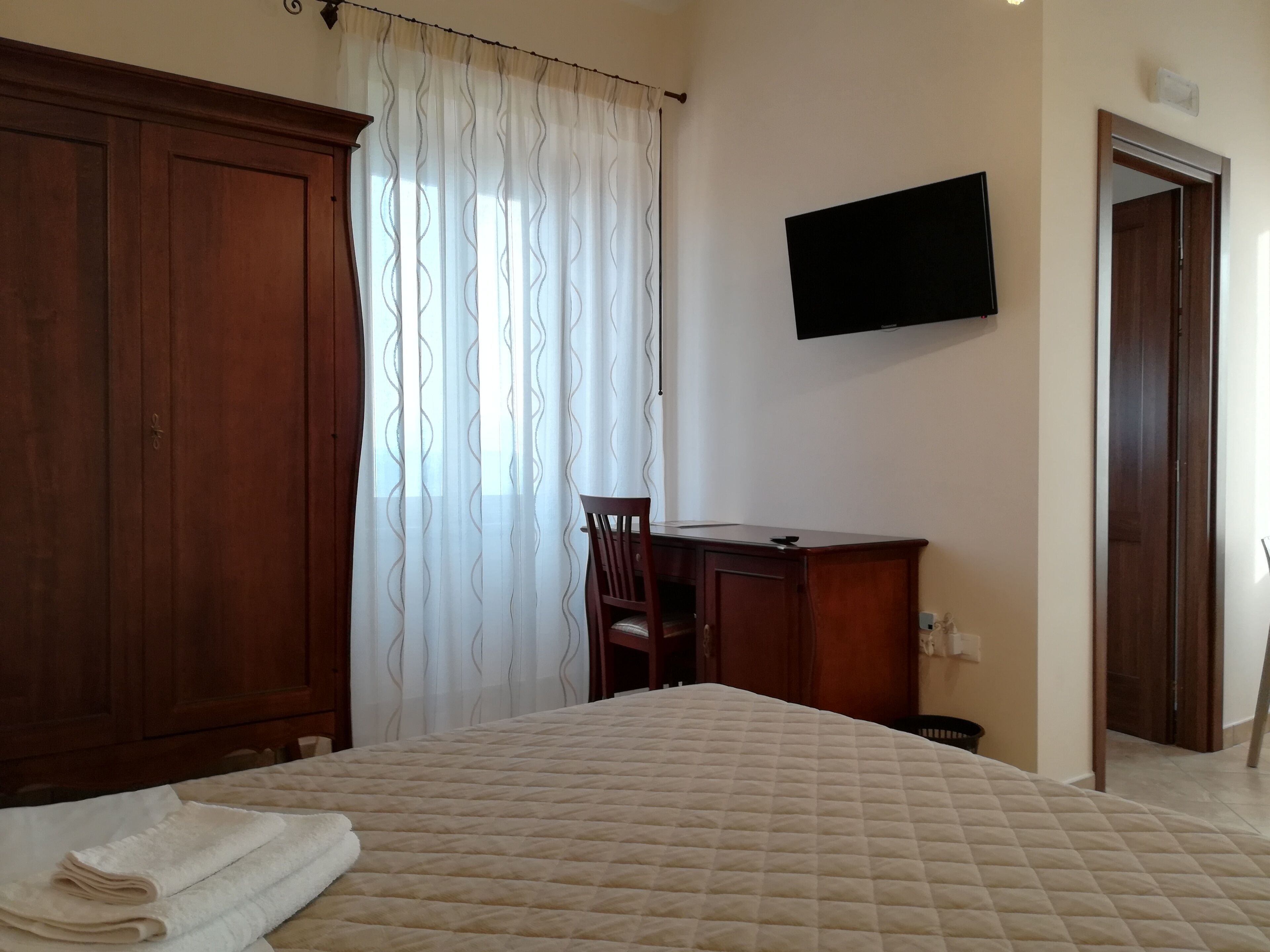 Une chambre d’hôtel comprenant un lit, un bureau, une chaise, une télévision et une armoire.