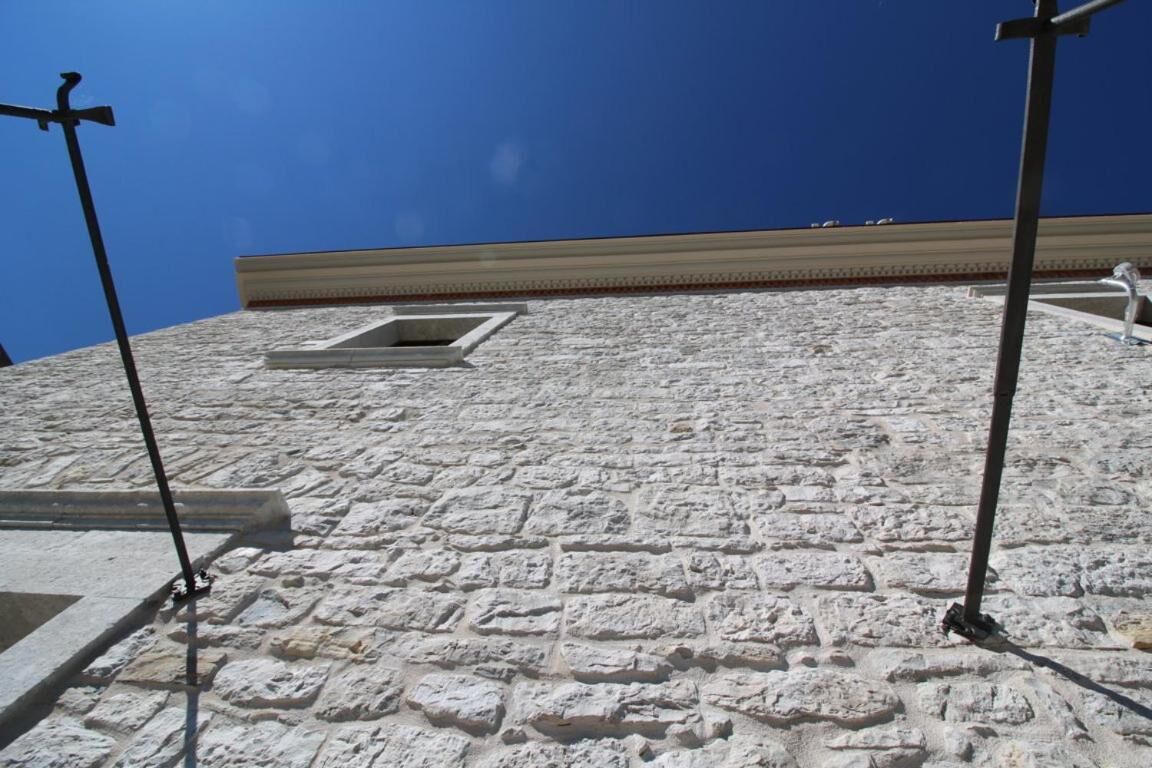 A stone wall with a window and metal poles.