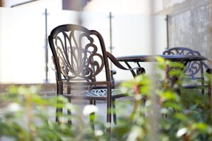 A metal chair with intricate backrest design, positioned outdoors with a table in the background. - Gästehaus Weingut Politschek (Bad Friedrichshall)
