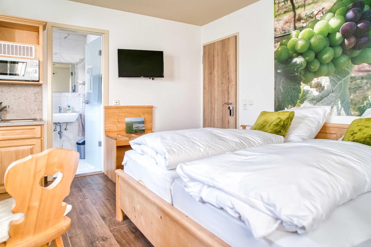A bedroom with two beds, a wooden headboard, a TV, and a wall-mounted TV.