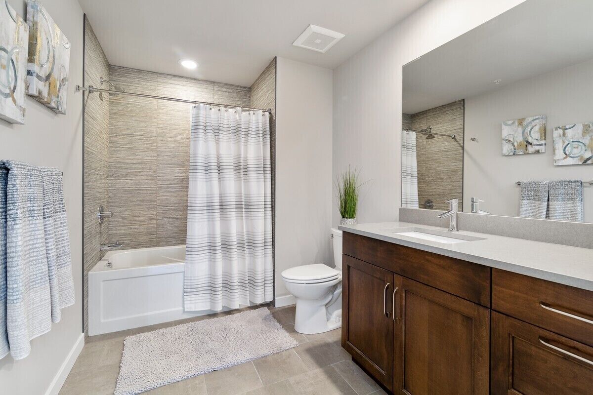 A modern bathroom with a bathtub, toilet, and vanity.