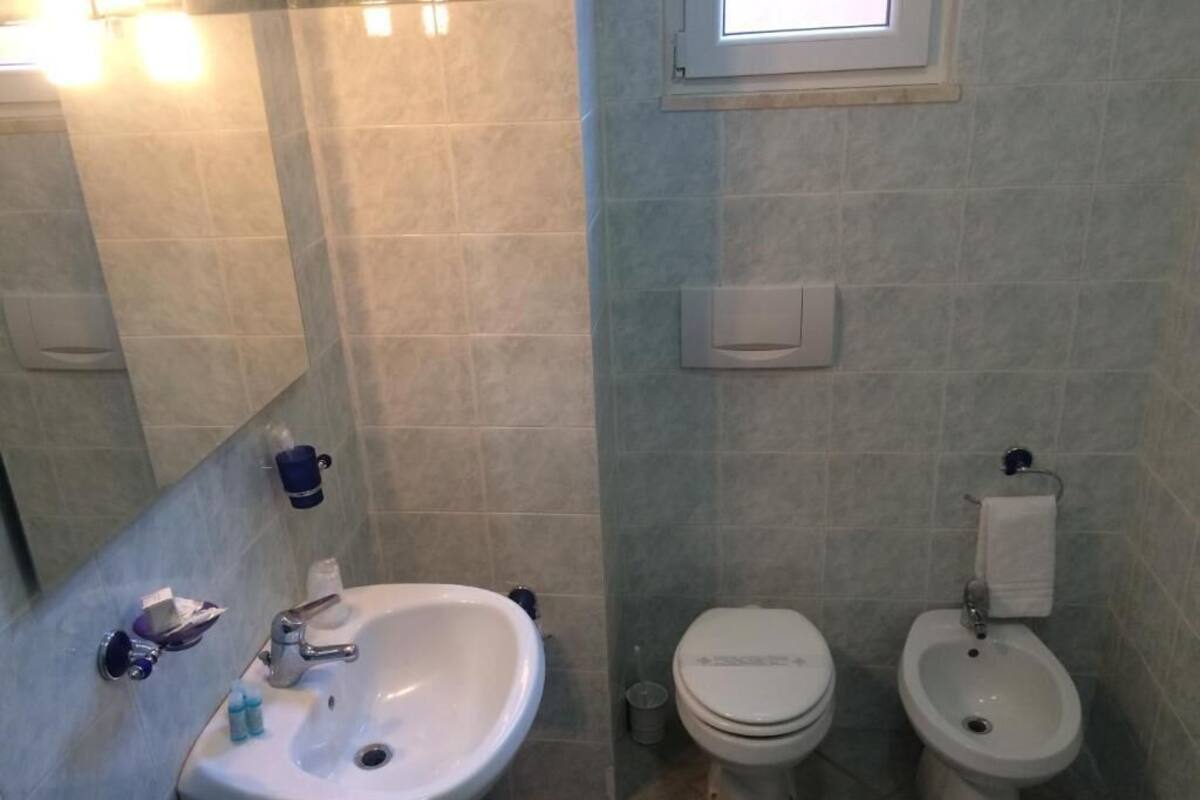Un baño con lavamanos, inodoro, bidé y espejo.