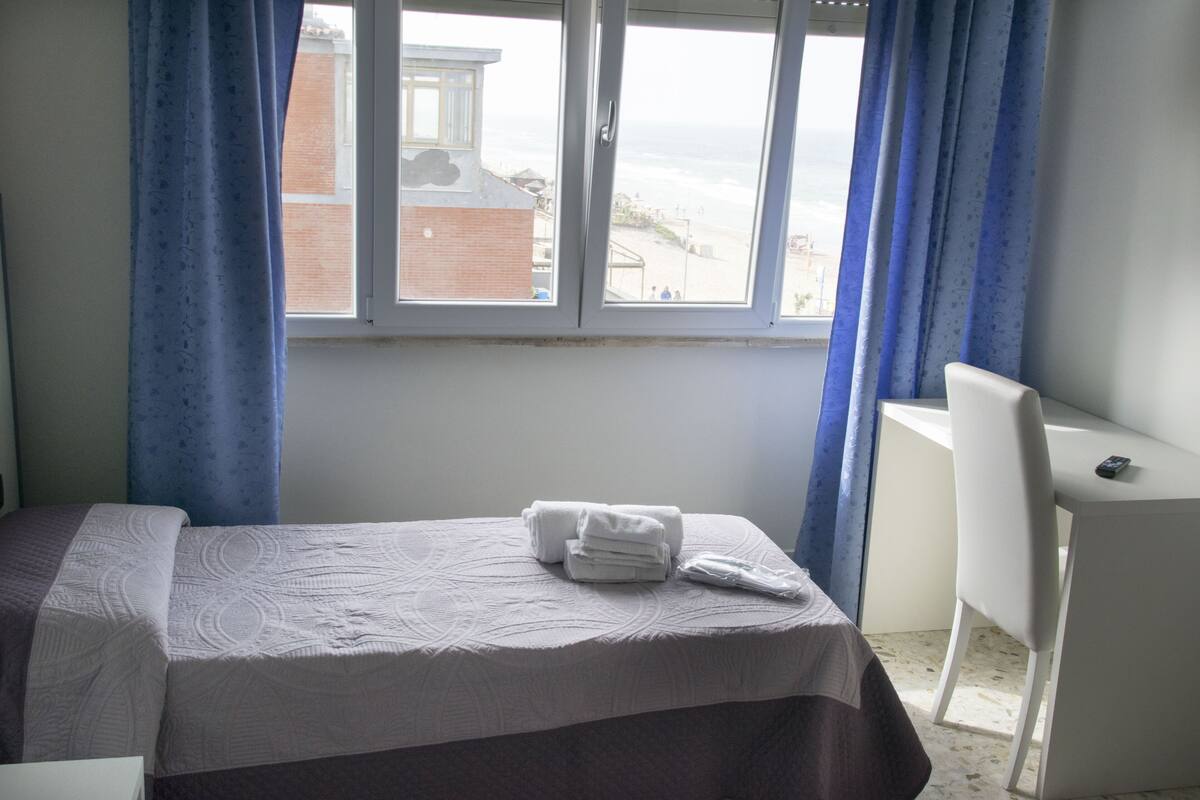 Una habitación de hotel con una cama, un escritorio y vistas a la playa.