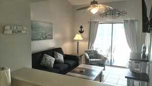 A living room with a sofa, armchair, lamp, and artwork. - Perfect for quite Beach Lovers. Four pools.Fall/Off Season Week-Month Specials!
 (Orange Beach)