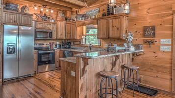 A wooden cabin kitchen with a central island, stainless steel appliances, and rustic decor.