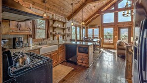 A spacious kitchen with wooden cabinets, a large island, and a view of the outdoors through large windows.
