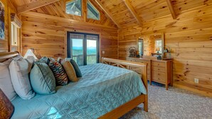Un dormitorio de cabaña de madera con cama, almohadas, escritorio y ventana.