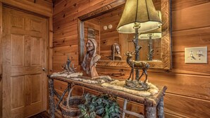 Un intérieur en bois avec un banc rustique, une lampe, un miroir et une porte.