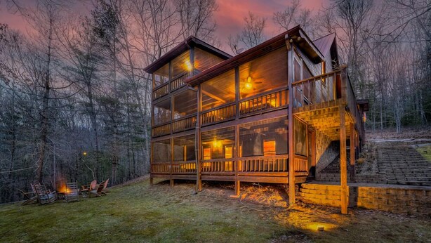 Une cabane en bois à deux étages, dotée d’un balcon et entourée d’arbres.