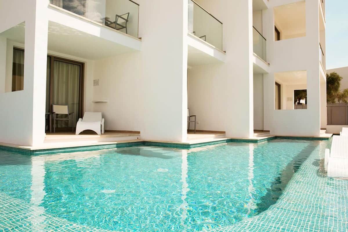 A modern hotel with a pool area, including a lounge chair and a small table.
