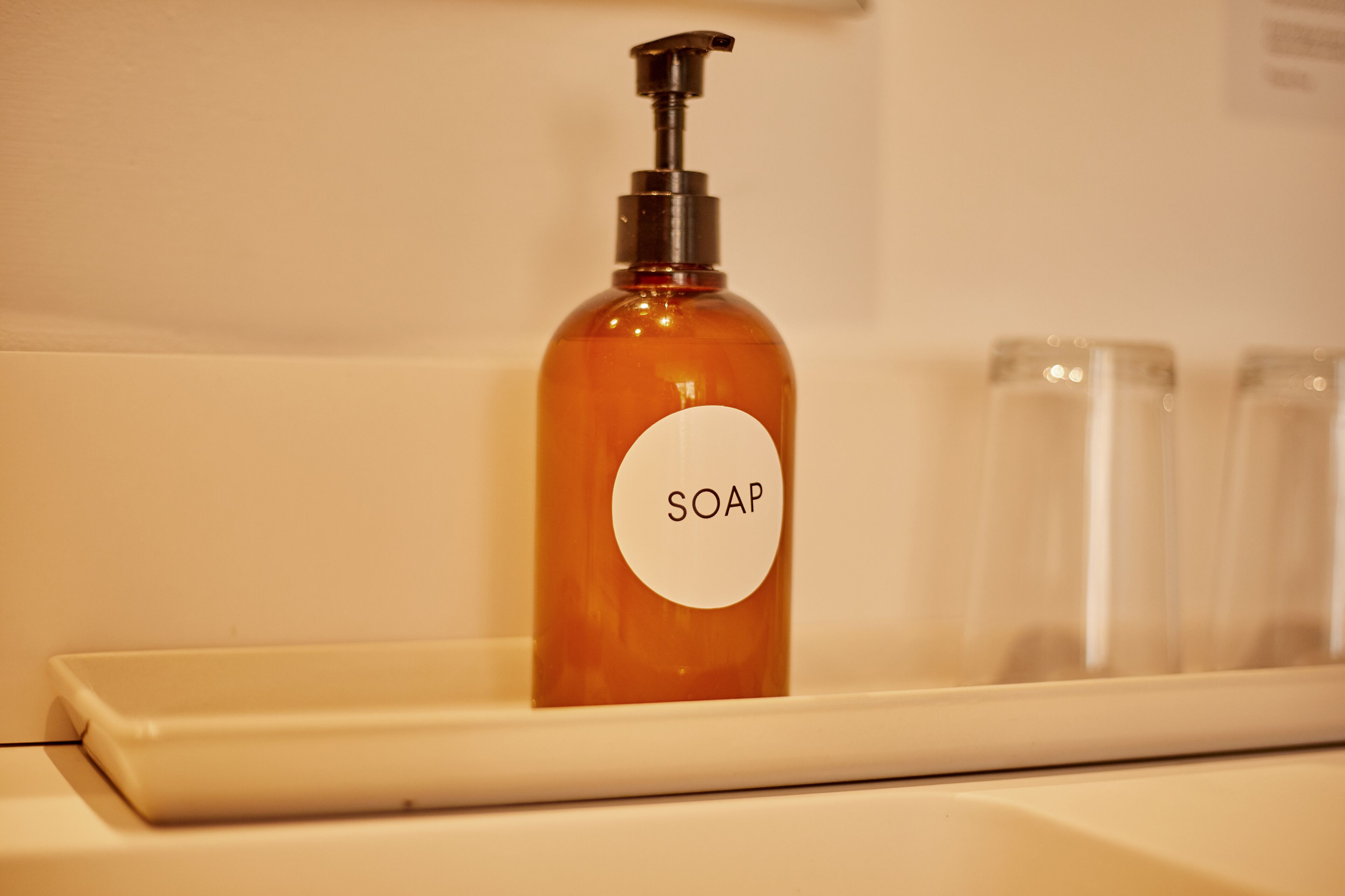 A bathroom with a soap dispenser on a white shelf.