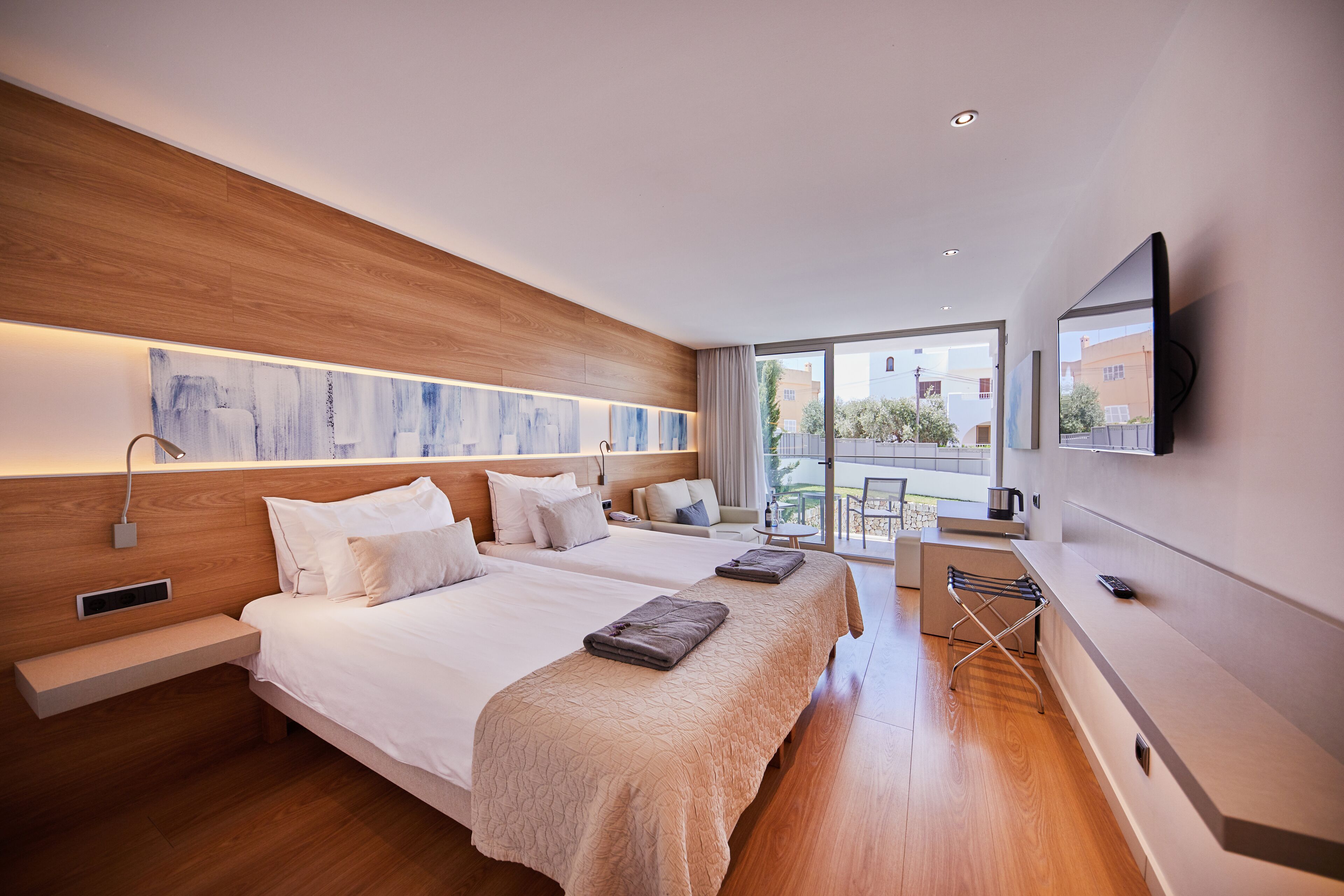A modern hotel room with two beds, a desk, and a balcony view.