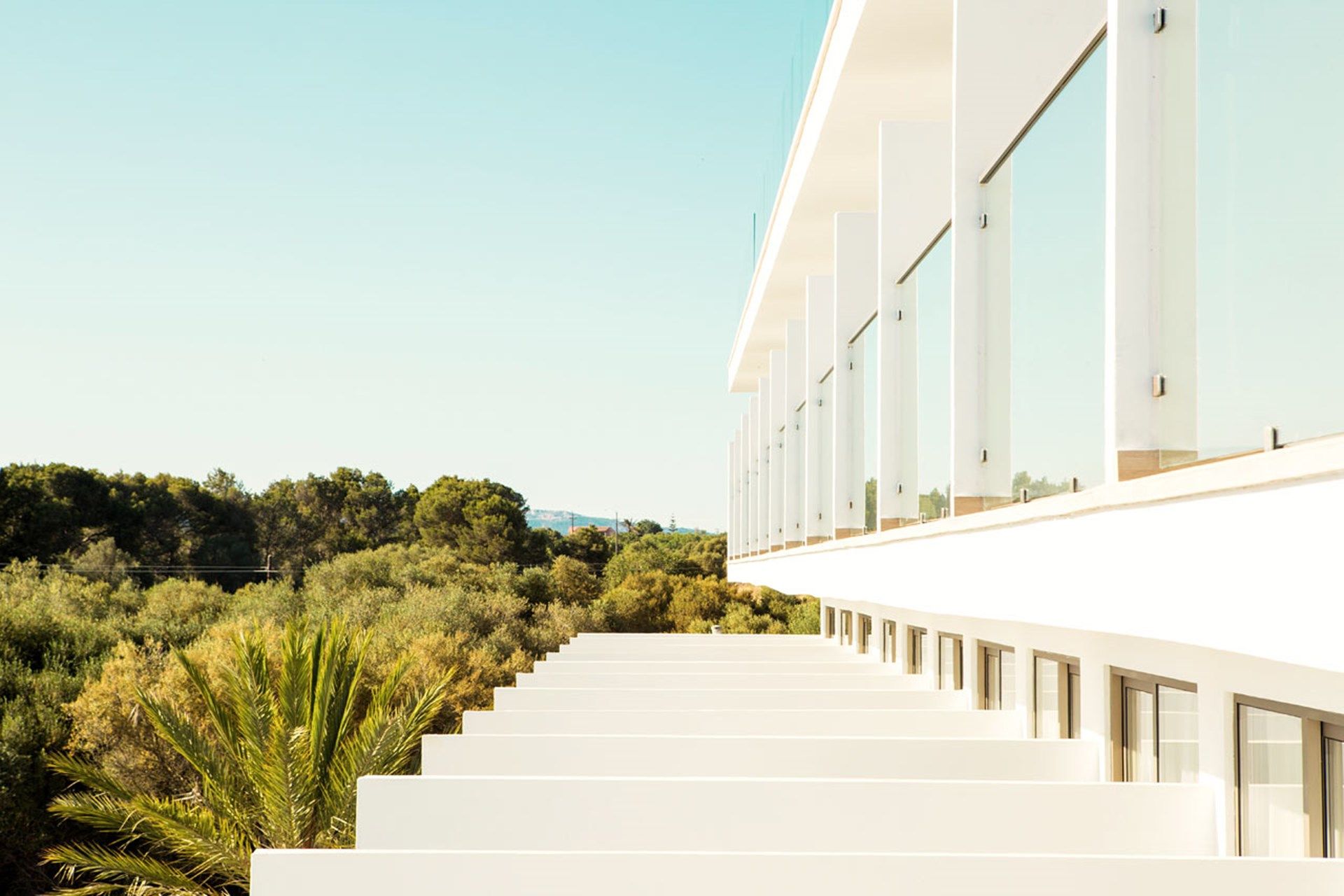 Un edificio moderno con una larga escalera recta que conduce a una fachada blanca con ventanas amplias.