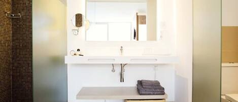 Un baño moderno con un espejo grande, tocador blanco y un perchero para toallas.