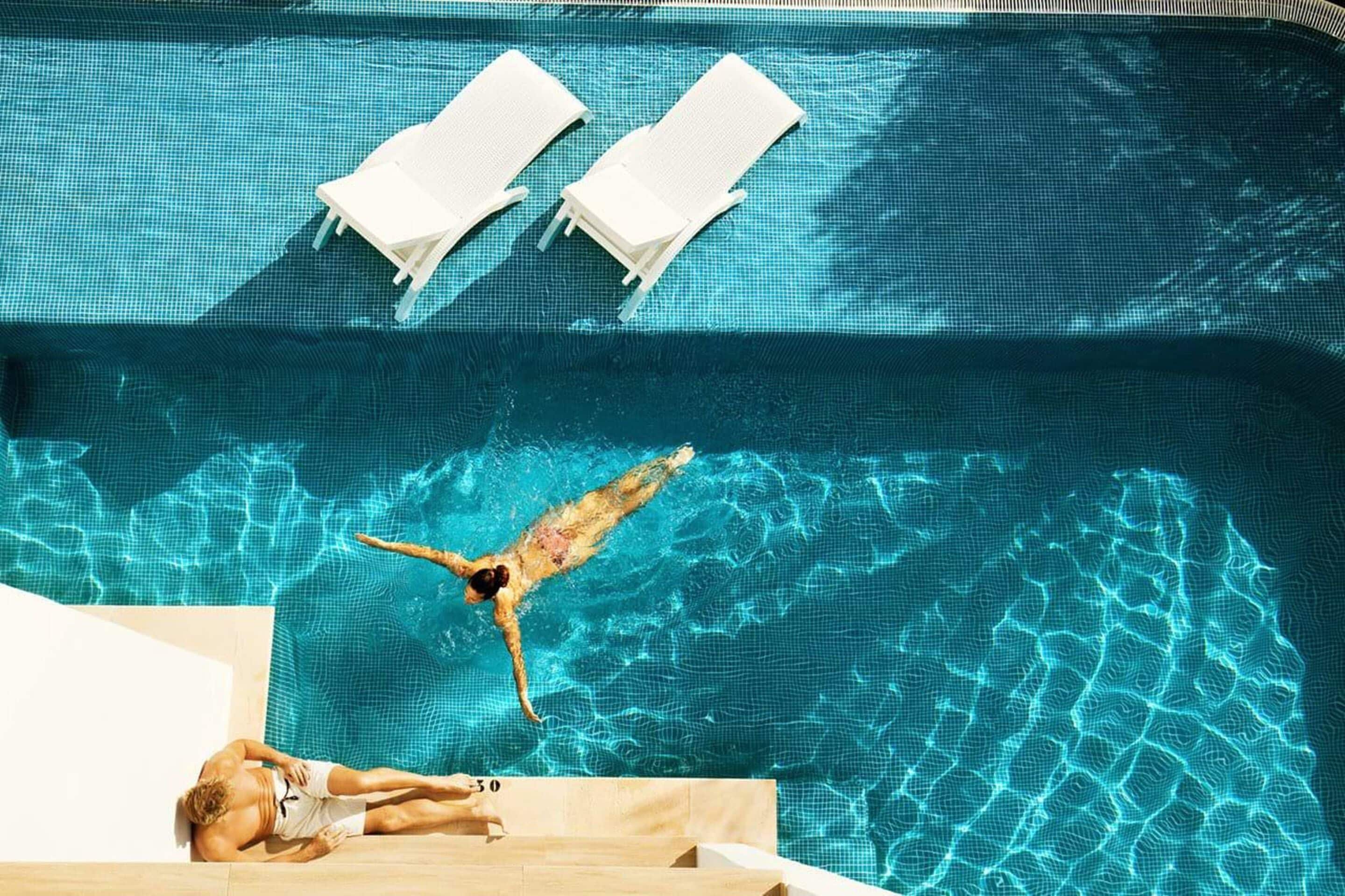 Ein Schwimmbecken mit zwei Liegestühlen und einer Schwimmerin.