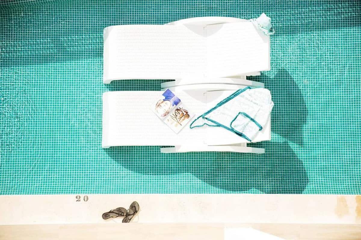 A poolside area with a tiled floor, a pair of flip-flops, and a towel.