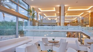 A modern lounge area with white sofas, round tables, and a glass railing overlooking a lower level. - Monsuau Cala D'Or Hotel - Adults Only (Felanitx)