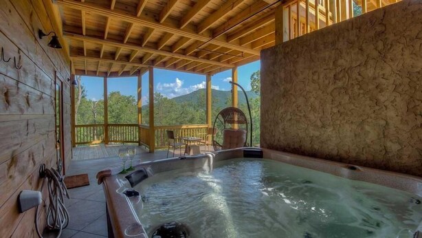Eine Holzhütte mit Whirlpool und Sitzgelegenheit im Freien.