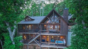 Een houten vakantiehuis met meerdere verdiepingen, een balkon en een jacuzzi op de tweede etage.