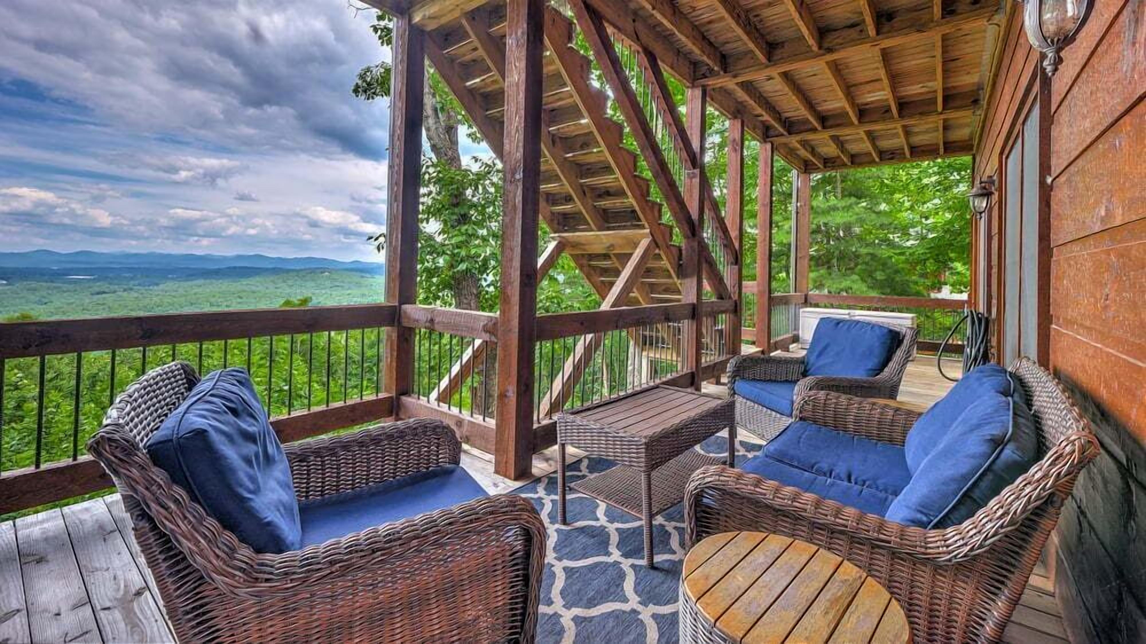 A covered outdoor seating area with wicker furniture and a view of a mountainous landscape.