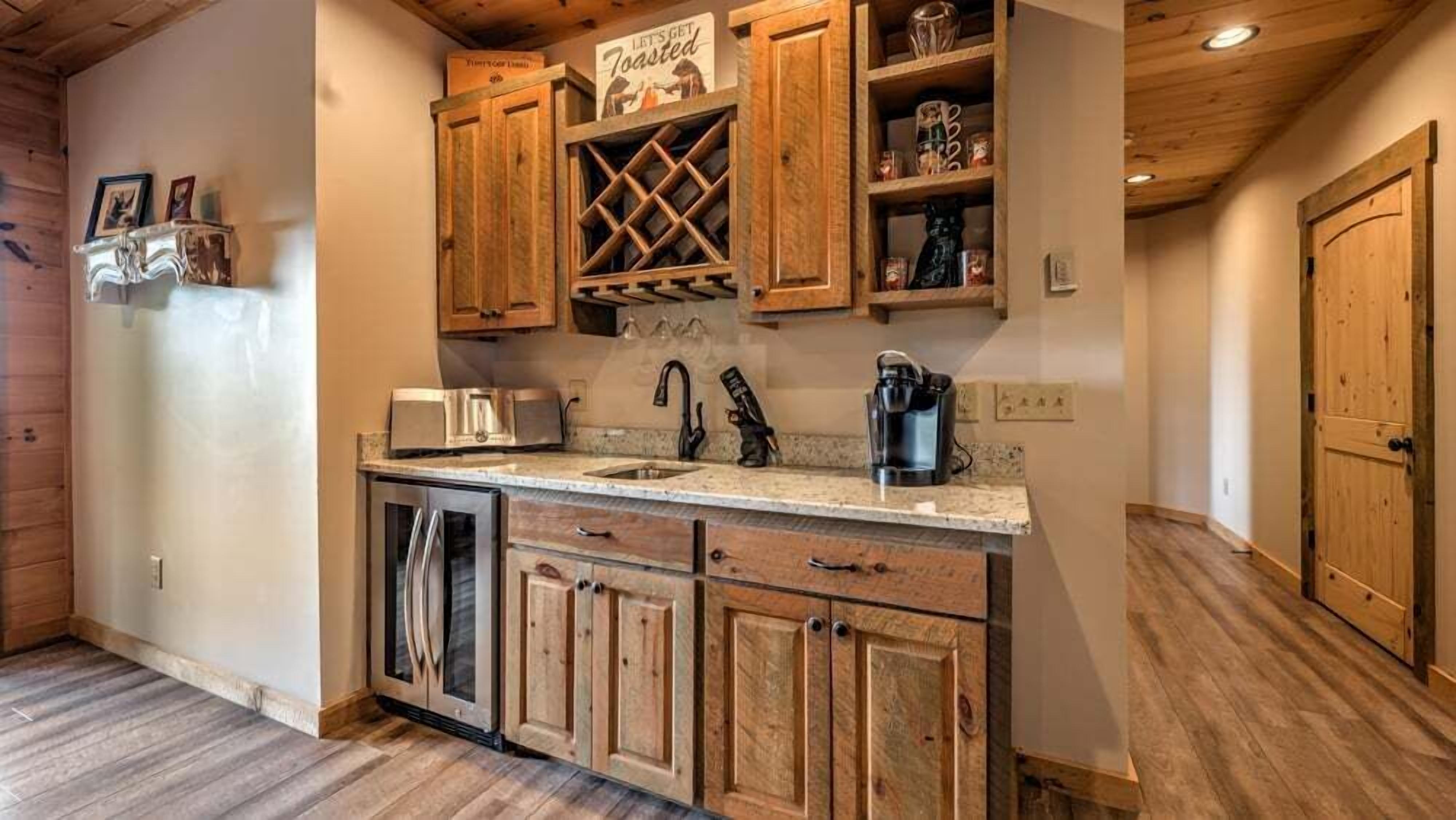 A kitchen with wooden cabinets, a stainless steel refrigerator, a coffee maker, and a wine rack.